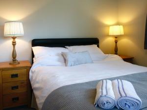 a bedroom with a large bed with towels on it at Willow Cottage in Bentley