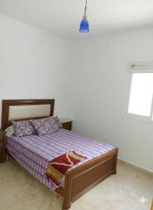a bedroom with a bed with purple sheets and a window at شفشاون in Chefchaouene
