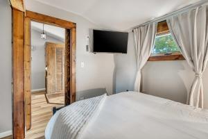 a bedroom with a bed and a flat screen tv at Craig Beach Cottage Hot Tub 5 Min Walk to Beach in Lake Milton