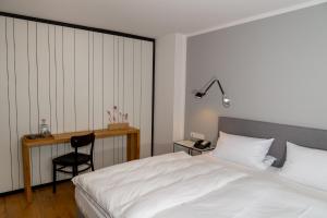 Un dormitorio con una cama blanca y un escritorio. en Der Hirschen, en Sankt Märgen