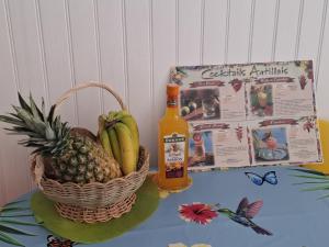 a basket of fruit and a bottle of cider and a basket of pineapple at Martinique 3 ILETS POINTE DU BOUT T2 35M2 in Les Trois-Îlets