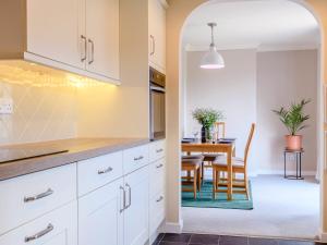 cocina con armarios blancos y comedor con mesa en Woodland, en Sheringham