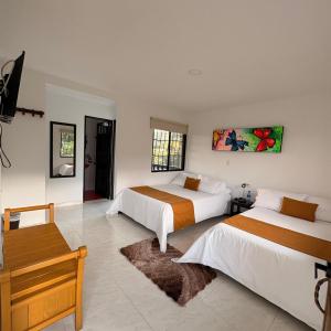 Un dormitorio con dos camas y un banco en él. en Hotel Campestre El Triunfo, en San Agustín