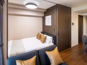 a hotel room with a bed and a chair at The Riverfront Residence Nishihiroshima in Hiroshima