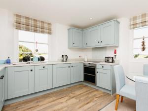 Una cocina blanca con gabinetes blancos y una mesa. en Charborough House Apt 3, en Salcombe