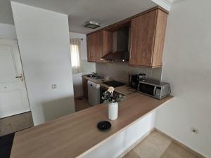 a kitchen with wooden cabinets and a counter with flowers on it at Sea and Sun Hills New Golden mille Flat 1 in Estepona