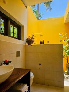 a bathroom with a yellow wall and a sink at Villa Akasa in Varkala +58 photos