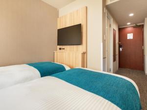 two beds in a hotel room with a flat screen tv at Villa Fontaine Tokyo Jimbocho in Tokyo