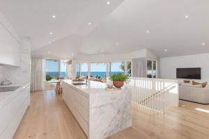 a kitchen and living room with white walls and wood floors at Seaviews at Sunshine Beach 4BR, Pool in Sunshine Beach