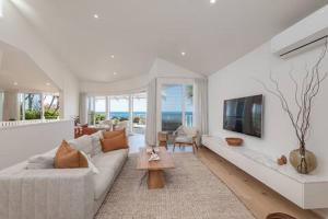 a living room with a white couch and a tv at Seaviews at Sunshine Beach 4BR, Pool in Sunshine Beach