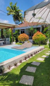 Un patio trasero con piscina y una casa. en Lila Boutik Residence, en Canggu