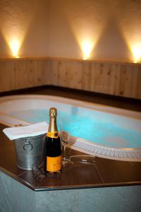 Una botella de champán y una copa junto a la bañera. en Alpengasthof Norbertshöhe Superior en Nauders