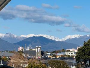 a city with snow covered mountains in the background at The Sundowner Beach Club in Hokitika