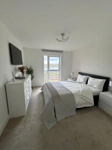 a white bedroom with a bed and a tv at Waterfront luxury apartment in Southampton