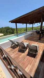 ChanoLuxury Dream Village in Palmarito Puerto Escondido的一个带椅子的木制甲板和游泳池