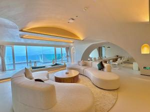 een woonkamer met witte meubels en uitzicht op de oceaan bij Cloud Coast Hotel in Kang-k'ou