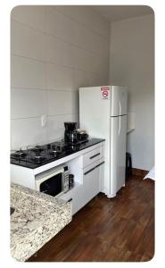 a kitchen with a stove and a white refrigerator at Ap.233-9 Central/St.Universitário/Goiânia. in Goiânia
