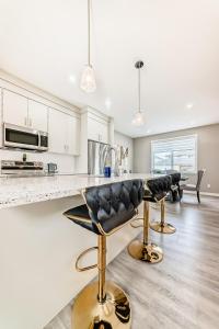 a kitchen with white cabinets and gold bar stools at Cozyhub Vacation Rental Calgary-3Bedroom with AC in Calgary