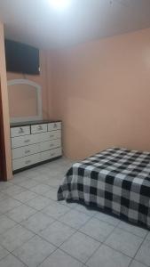 a bedroom with a bed and a dresser and a mirror at Artur House Alojamiento in Manta