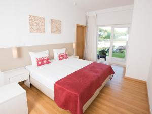 a white bedroom with a large white bed with red pillows at Tavira Monte in Tavira