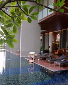 a woman sitting on the edge of a pool in a hotel at Hansar Bangkok Hotel in Bangkok