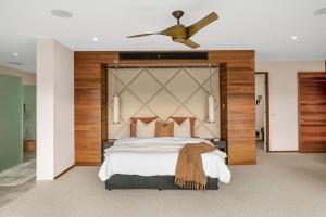 a bedroom with a large bed with a ceiling fan at Your Own Luxury Coastal Beachfront Wellness Retreat 14 sleeps in Casuarina