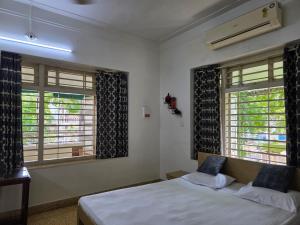 a bedroom with a bed and two windows at Srinekatan Heritage Villa Homestay in Ahmedabad
