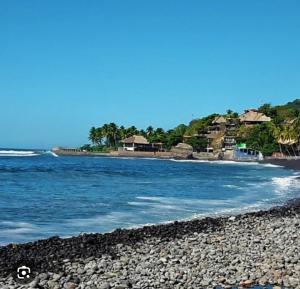a beach with a rocky shore with houses and the ocean at La ceibasurf in La Libertad