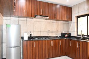 Una cocina con gabinetes de madera y un refrigerador de acero inoxidable. en TRENDY RESIDENCE - Luxury Serviced Apartments in Bastos, en Yaoundé