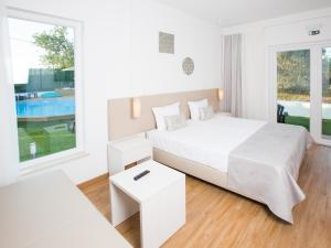 a white bedroom with a large bed and a pool at Tavira Monte in Tavira +37 photos