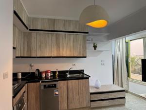 eine Küche mit Holzschränken und Spüle und einem Fenster in der Unterkunft رويال روف بالتجمع الخامس أمتداد الجامعة الامريكية in New cairo