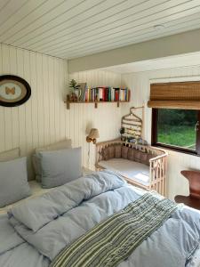 a bedroom with two beds and a window and a crib at Nordic-Style Summer House At Asserbo Plantage in Melby +12 photos