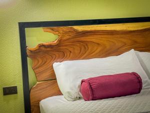 - un lit avec une tête de lit en bois et un oreiller rouge dans l'établissement Monte Green Villa Romántica con jacuzzi, à Monteverde Costa Rica