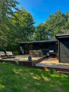 a log cabin with a deck and benches on it at Nordic-Style Summer House At Asserbo Plantage in Melby