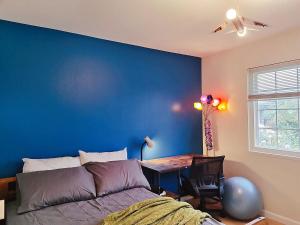 Un dormitorio con una pared azul, una cama y una mesa. en Tranquil Fremont Getaway - Comfortable 3BR 2BA Home, en Fremont