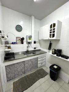 Una cocina con un fregadero y un reloj en la pared. en Quarto Privativo Leme de Noronha - 2Min da praia, en Río de Janeiro