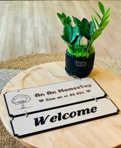 a welcome sign on a table with a potted plant at An An Homestay- Ecopark- Văn Giang- Hưng Yên in HÆ°ng YÃªn