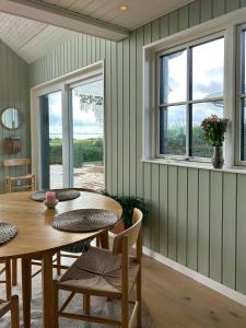 ein Esszimmer mit Tisch und Stühlen und Fenstern in der Unterkunft Holiday Home With Sea View Near Hesselager in Hesselager
