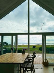 a wooden table and chairs on a porch with a large window at Holiday Home With Sea View Near Hesselager in Hesselager