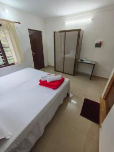 Un dormitorio con una cama blanca con toallas rojas. en John's Heaven Valley, en Idukki