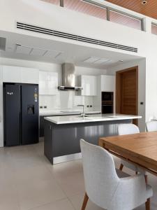 a kitchen with a black refrigerator and a wooden table at Luxury Villa Phuket in Phuket