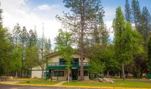 une maison avec une véranda verdoyante et des arbres dans l'établissement Yosemite Lakes Bunkhouse Cabin 27, à Harden Flat