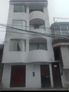 un edificio alto de color blanco con puertas y ventanas rojas en Condominio Las Torres, en Ayacucho