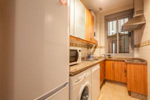 a kitchen with a washer and a white refrigerator at SevillaHome -Alfareria in Seville