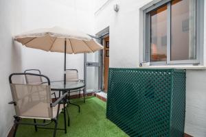 a table and chairs with an umbrella in a room at SevillaHome -Alfareria in Seville
