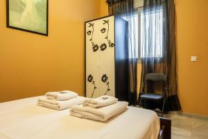 1 dormitorio con 1 cama con toallas en SevillaHome -Alfareria, en Sevilla