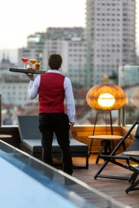 a man holding a tray of food on a rooftop at Palacio de los Duques Gran Meliá - The Leading Hotels of the World in Madrid