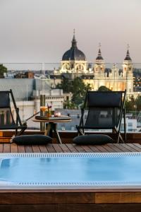 two chairs and a table next to a swimming pool at Palacio de los Duques Gran Meliá - The Leading Hotels of the World in Madrid