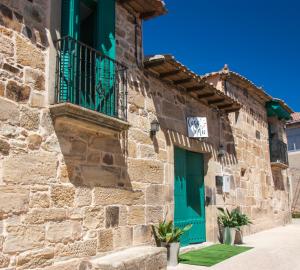 un edificio in pietra con porta verde e balcone di Hotel Rural Casa Indie a Rabanal del Camino