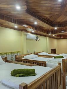 a group of beds in a room with wooden ceilings at Sunset Backpackers Hostel in Nongkhiaw